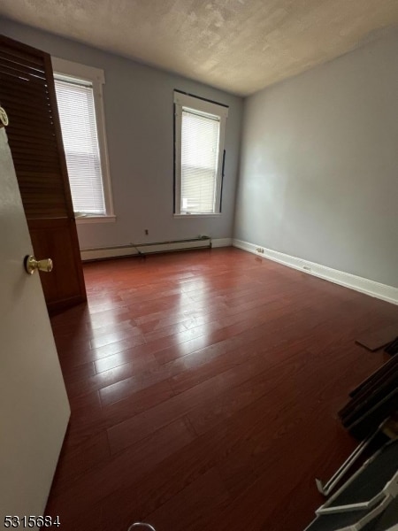 empty room featuring a wealth of natural light, a textured ceiling, and hardwood / wood-style flooring