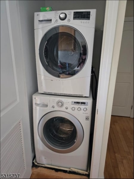 clothes washing area featuring wood-type flooring and stacked washer and clothes dryer