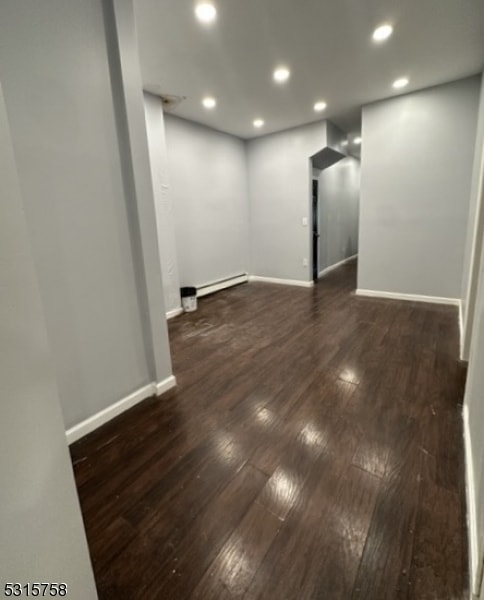 basement featuring a baseboard radiator and dark hardwood / wood-style flooring