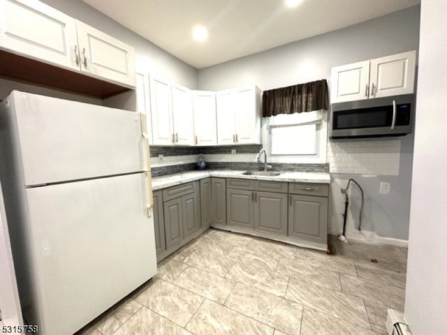 kitchen featuring gray cabinets, white cabinetry, white fridge, and sink