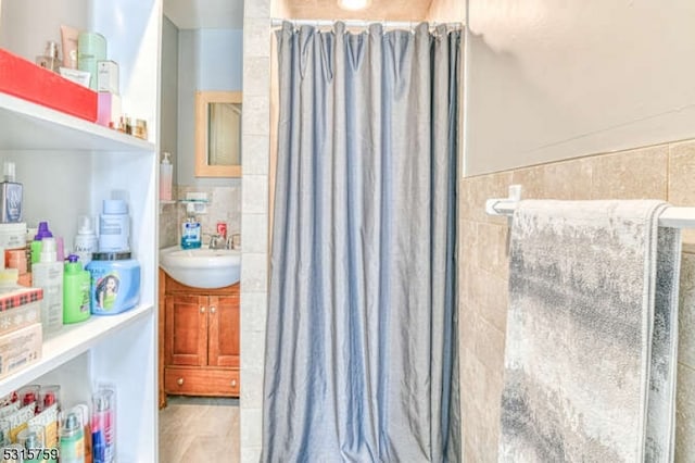 bathroom with tile walls, vanity, and a shower with curtain