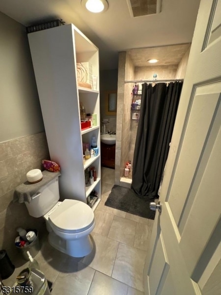 bathroom featuring toilet, tile patterned flooring, and a shower with shower curtain