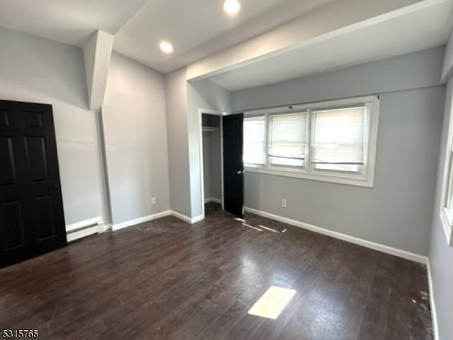 unfurnished bedroom featuring baseboard heating and dark hardwood / wood-style floors