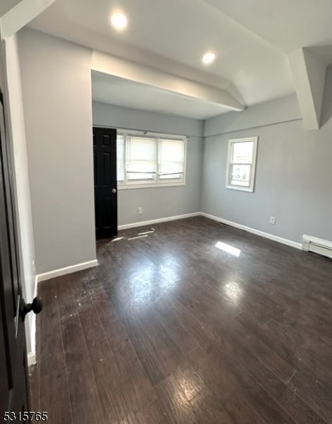 spare room featuring beamed ceiling and dark hardwood / wood-style floors