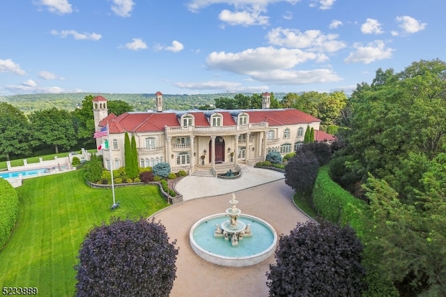 back of property featuring a balcony, a lawn, and a patio area