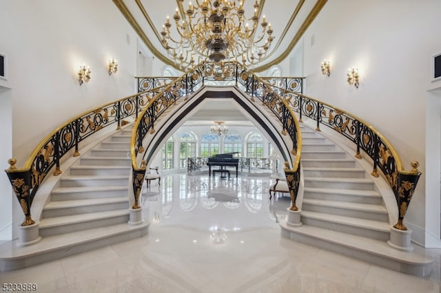 staircase featuring ornamental molding, an inviting chandelier, and a high ceiling