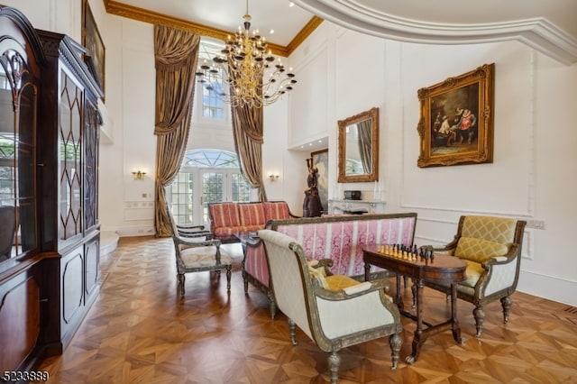 living area featuring parquet floors, ornamental molding, a towering ceiling, and a chandelier