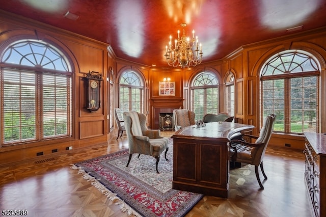 dining room featuring an inviting chandelier, wood walls, light parquet floors, and crown molding