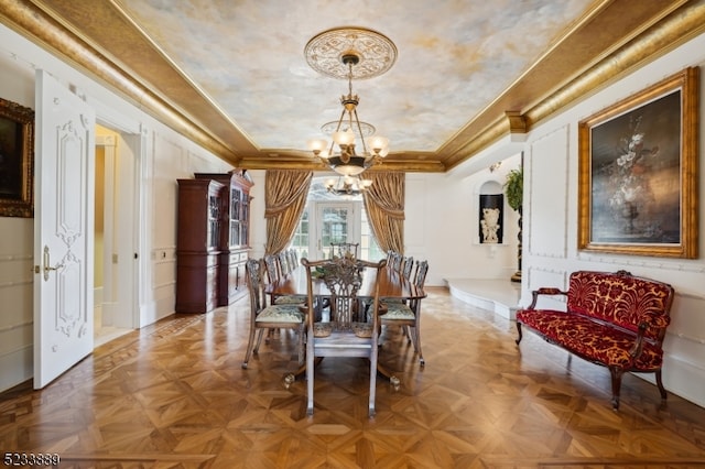 dining space featuring ornamental molding, an inviting chandelier, and parquet flooring