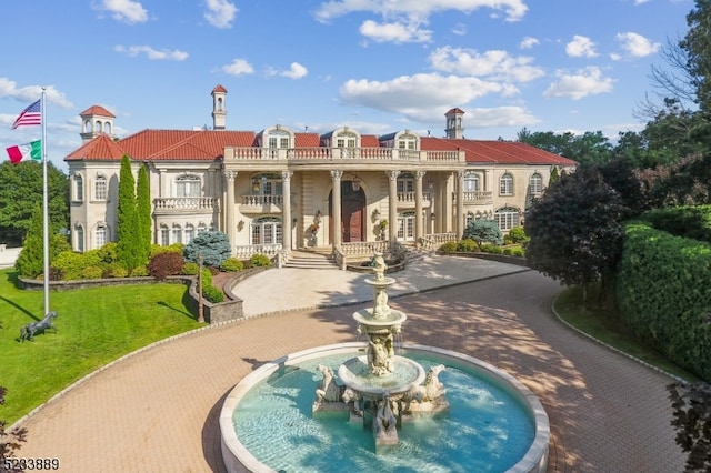 rear view of property featuring a lawn and a balcony