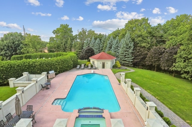 view of swimming pool featuring an in ground hot tub, a lawn, a patio area, and an outbuilding