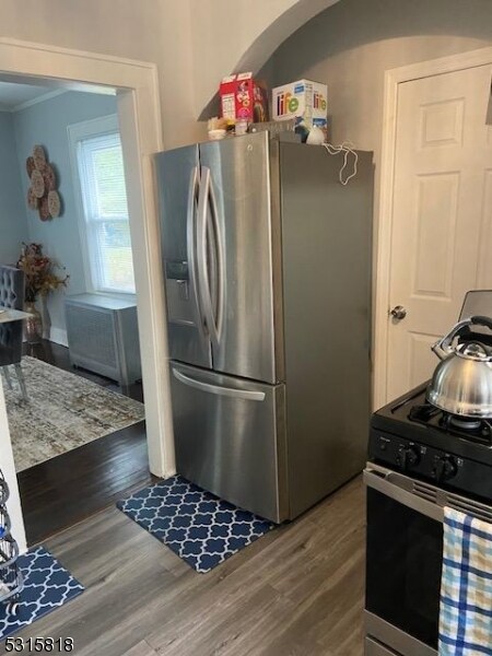 kitchen with appliances with stainless steel finishes, dark wood-type flooring, and crown molding