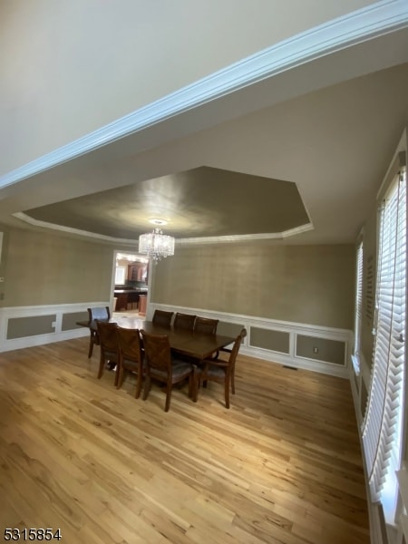 dining area featuring hardwood / wood-style floors, crown molding, and an inviting chandelier