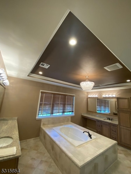 bathroom featuring a relaxing tiled tub, vanity, and an inviting chandelier