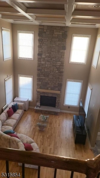 living room with hardwood / wood-style floors, a fireplace, a high ceiling, and coffered ceiling