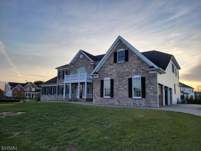 view of front of property with a lawn, a garage, a balcony, and central AC