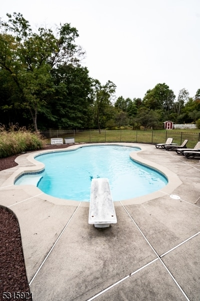 view of swimming pool featuring a diving board and a patio area