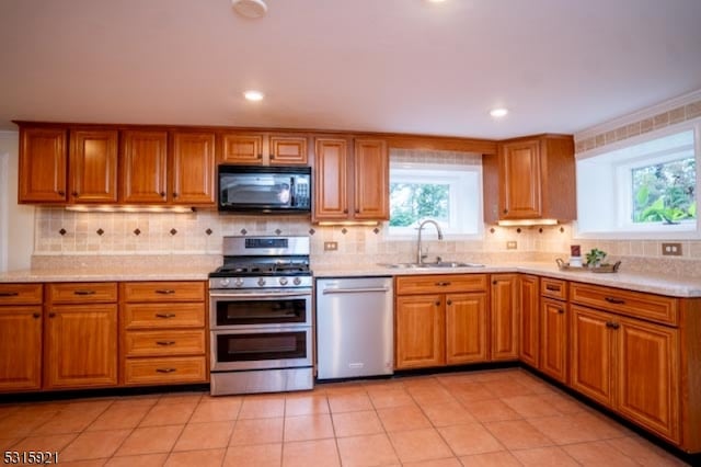 kitchen featuring light tile patterned floors, sink, stainless steel appliances, crown molding, and decorative backsplash