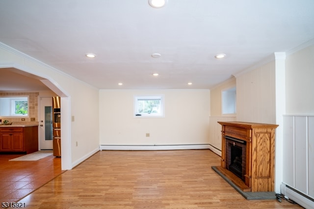 unfurnished living room featuring crown molding, light hardwood / wood-style floors, and a baseboard heating unit