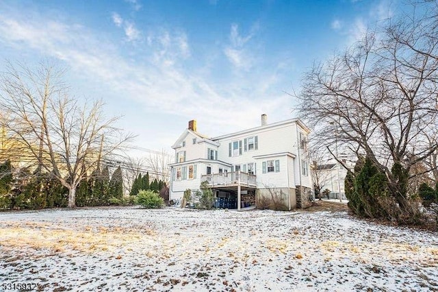 snow covered back of property with a wooden deck