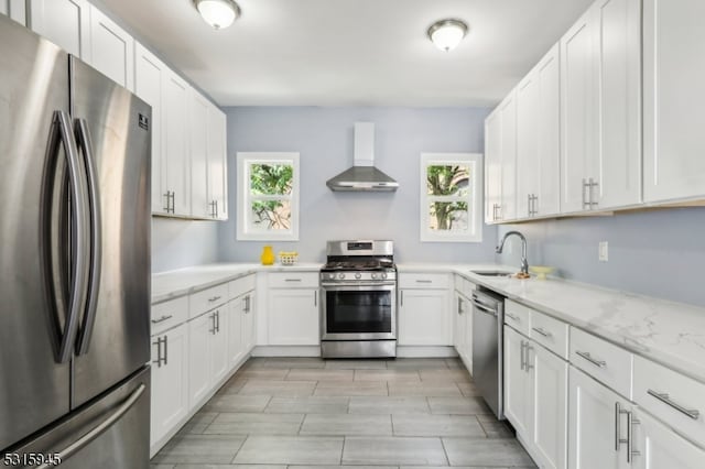 kitchen featuring appliances with stainless steel finishes, sink, wall chimney range hood, and a healthy amount of sunlight