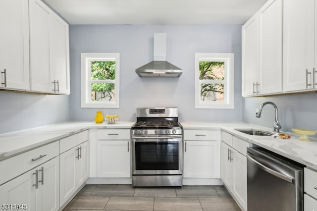 kitchen featuring a healthy amount of sunlight, appliances with stainless steel finishes, wall chimney range hood, and sink