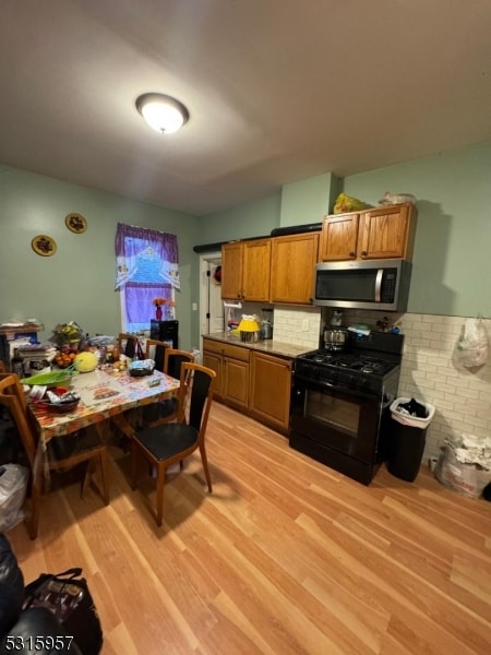 kitchen featuring light hardwood / wood-style flooring, backsplash, and black gas range oven