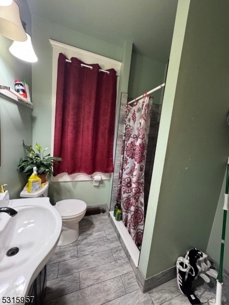 bathroom with sink, toilet, and curtained shower