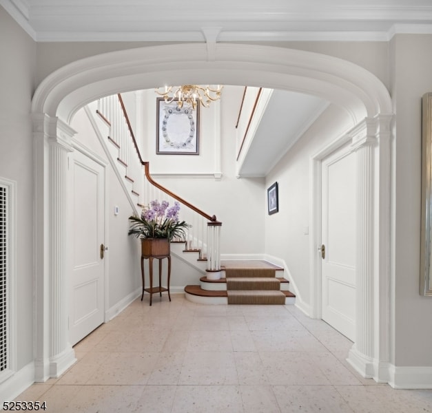 entryway with a notable chandelier and ornamental molding