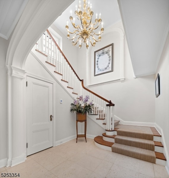 entryway with an inviting chandelier and crown molding