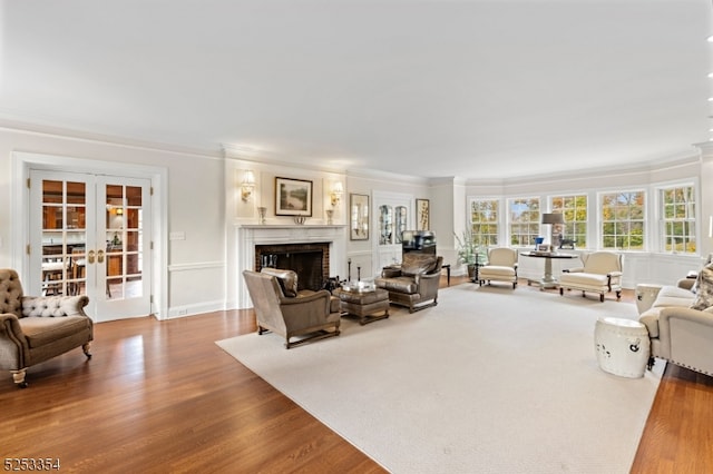 living room featuring wood-type flooring, ornamental molding, french doors, and a brick fireplace