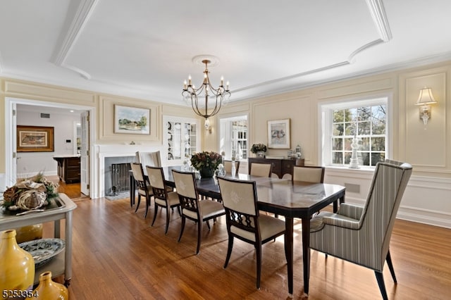 dining space featuring wood-type flooring, a notable chandelier, and ornamental molding