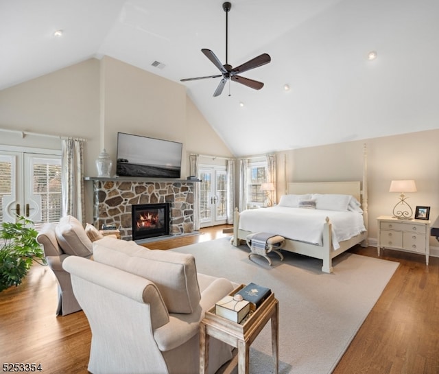 bedroom with high vaulted ceiling, a fireplace, access to exterior, light wood-type flooring, and ceiling fan