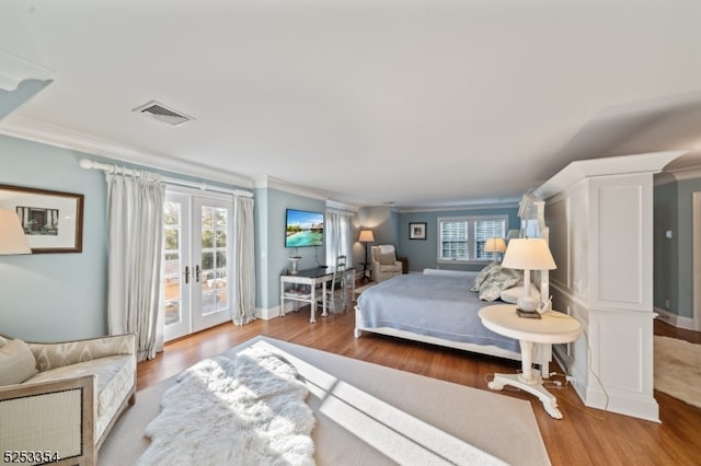 bedroom with ornamental molding, wood-type flooring, and multiple windows