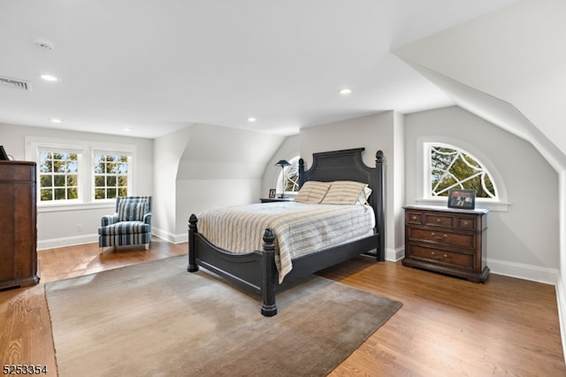 bedroom featuring multiple windows, vaulted ceiling, and hardwood / wood-style flooring