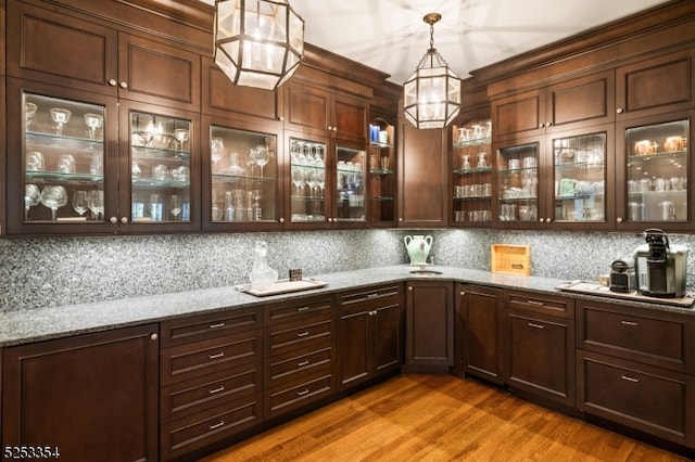 bar with dark hardwood / wood-style floors, backsplash, light stone countertops, and pendant lighting