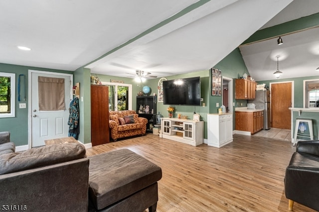 living room with ceiling fan, light wood-type flooring, vaulted ceiling, and a healthy amount of sunlight