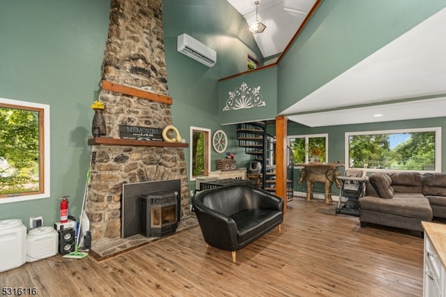 living room with high vaulted ceiling, light hardwood / wood-style flooring, a wood stove, and a wall mounted AC