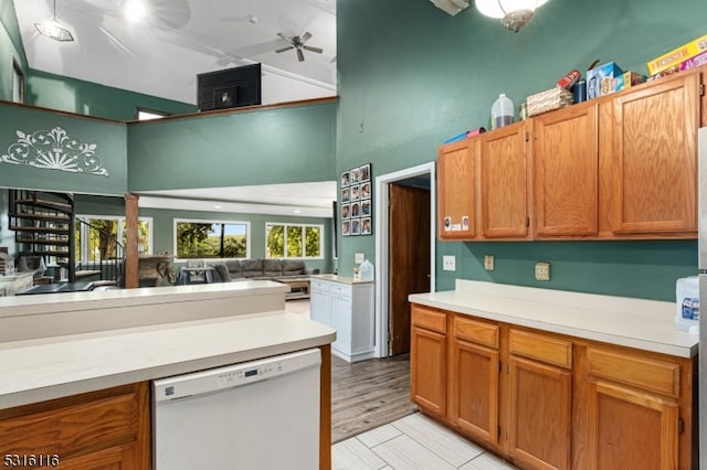 kitchen with ceiling fan, dishwasher, light hardwood / wood-style floors, and a high ceiling