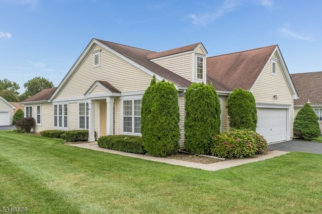 cape cod-style house featuring a garage and a front lawn