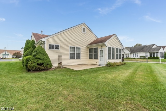 rear view of property featuring a sunroom, a patio area, and a yard