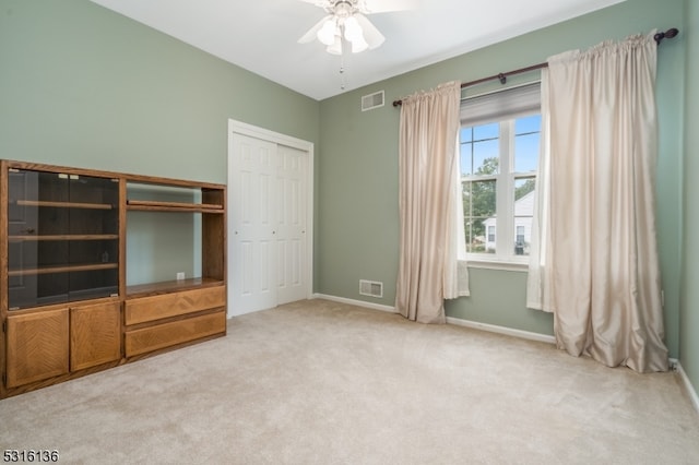 unfurnished bedroom featuring light carpet, a closet, and ceiling fan