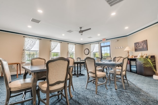 carpeted dining area with ornamental molding, ceiling fan, and plenty of natural light