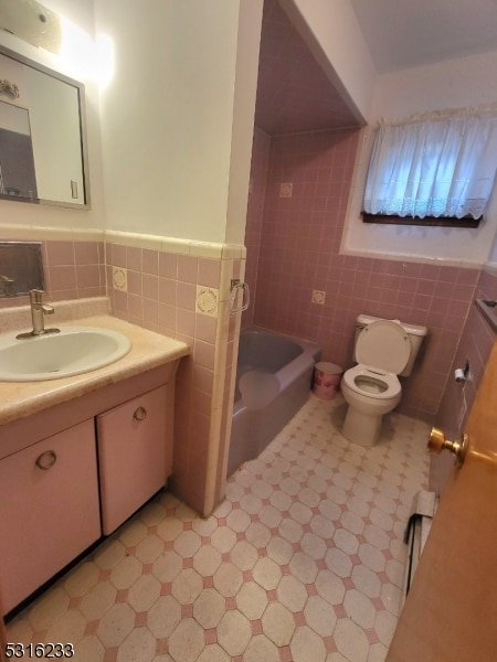 full bathroom with tile walls, vanity, shower with separate bathtub, and toilet