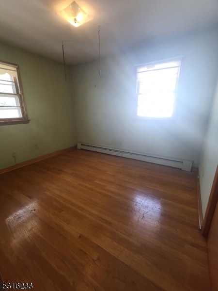 spare room with baseboard heating and dark hardwood / wood-style flooring