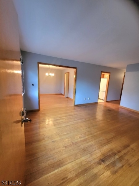 empty room with a chandelier and light wood-type flooring