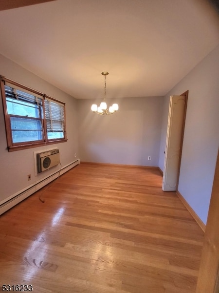 unfurnished dining area with a baseboard radiator, a chandelier, and light wood-type flooring