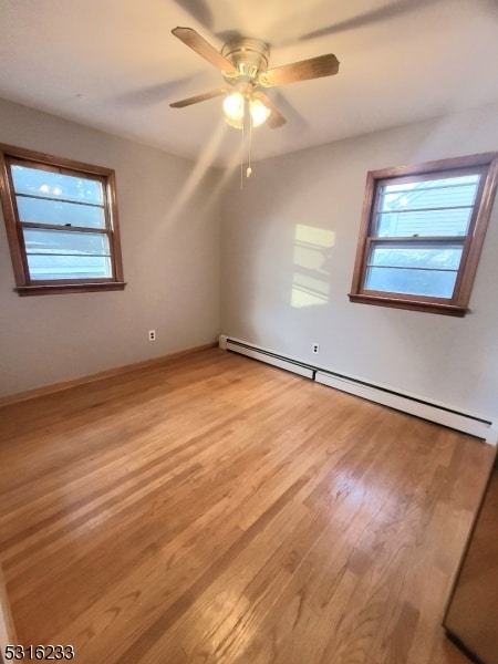 empty room featuring light hardwood / wood-style floors, a baseboard heating unit, and ceiling fan