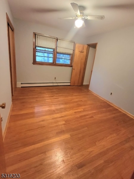 unfurnished bedroom featuring light hardwood / wood-style floors, baseboard heating, and ceiling fan