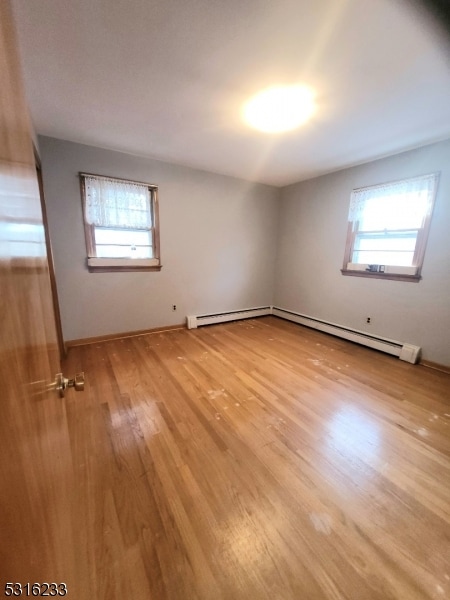 empty room with baseboard heating and light wood-type flooring